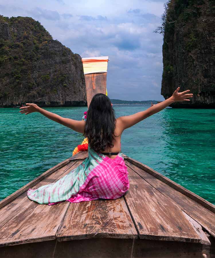 Lady on a boat with her arms stretched out near Phi Phi Island Thailand