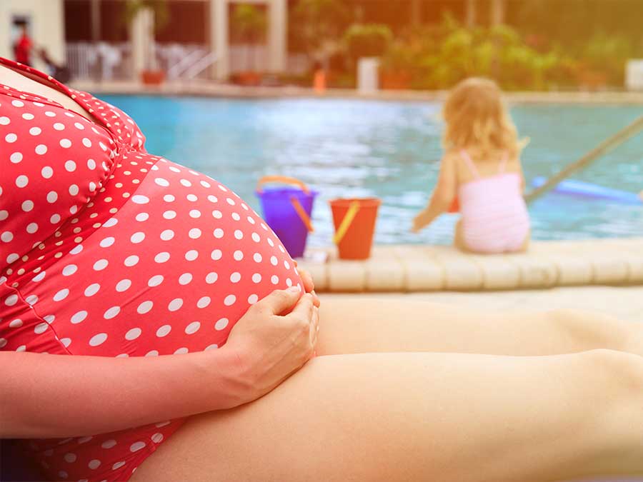 Pregnant mum relaxing by the poolside