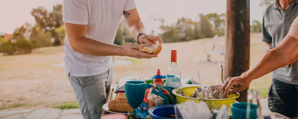 Two people preparing food at a picnic table