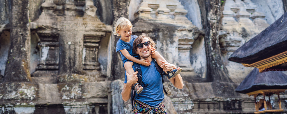 Father with son on shoulders in front of a temple