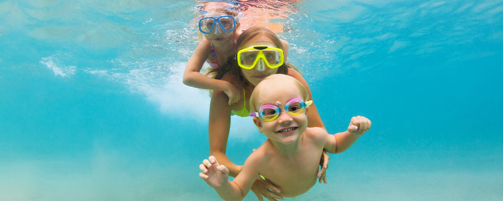 Family swimming underwater with goggles on
