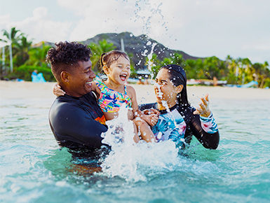Family playing in the ocean with a beach in the background
