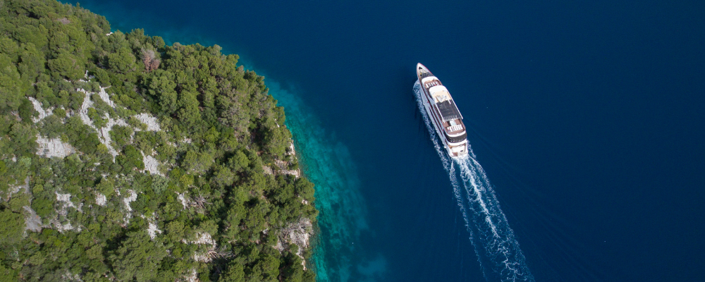 Aerial view of cruise ship moving through water next to island