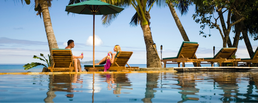Couple sitting on loungers next to pool overlooking the ocean