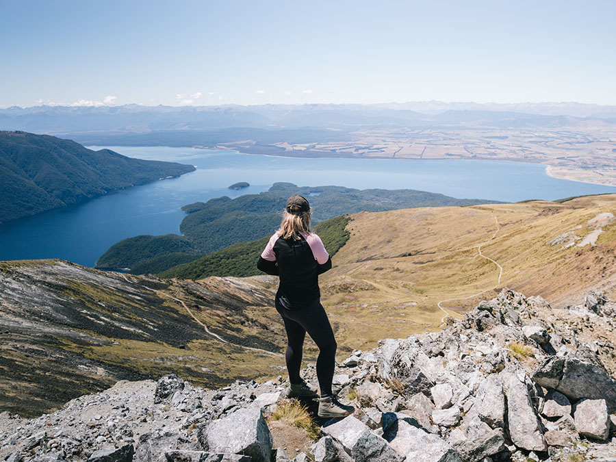 A woman stood at the top of a mountain after a hike looking at the beautiful view.