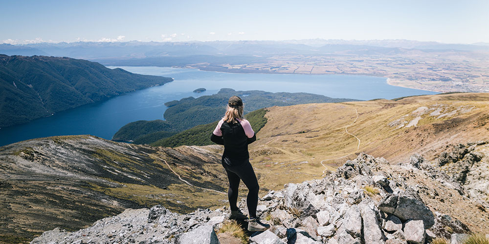 A woman stood at the top of a mountain after a hike looking at the beautiful view.
