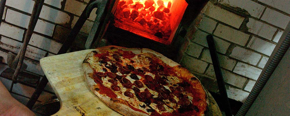 Pizza coming out of wood fire oven