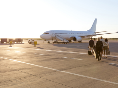 Group of people walking towards plane on tarmac 